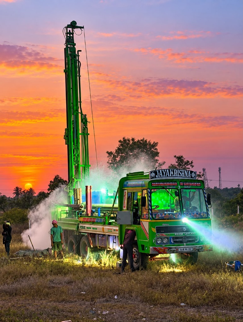 Live high-pressure borewell drilling operation at sunset